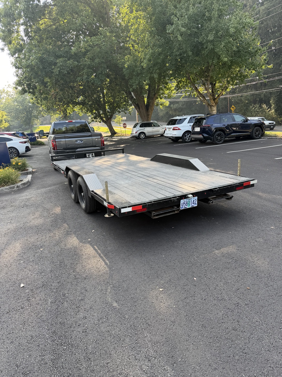 Roadside flat-deck car hauler connected to a pickup at the rental lot